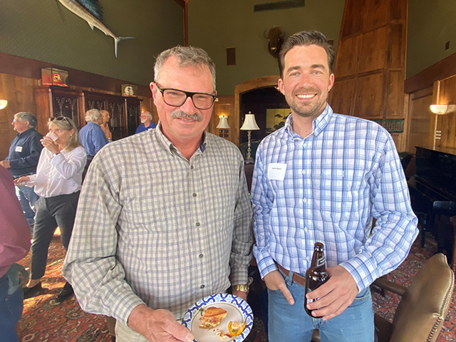 Two men, smiling, at a festive event in a beautiful house.