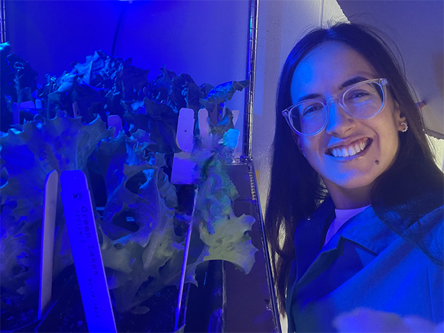 Close-up of a woman in a small room with dark blue-purple light.