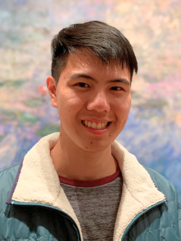 Man smiles in front of colorful background