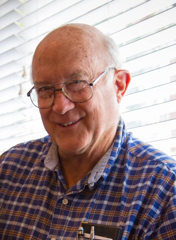 An older man wearing glasses and smiling.