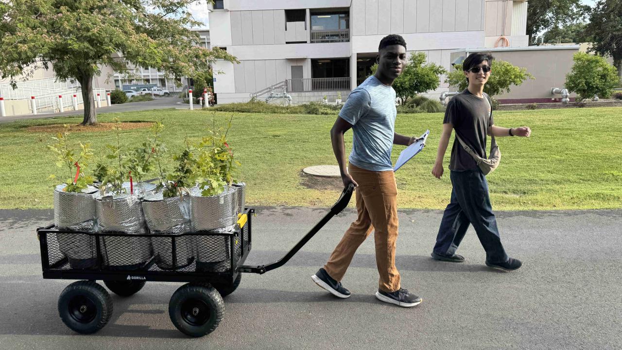 Two graduate students moving a cart with materials
