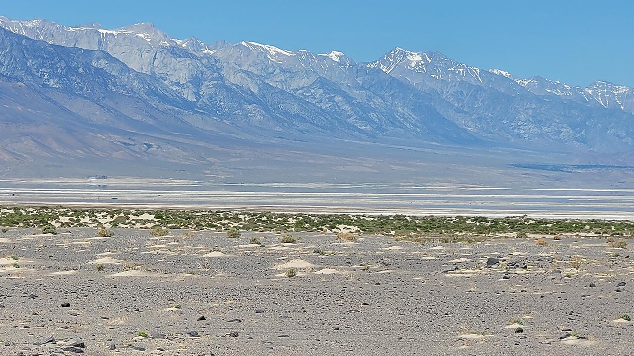 Dry ground, with mountains in the hazy distance. They have a little snow on the peaks.