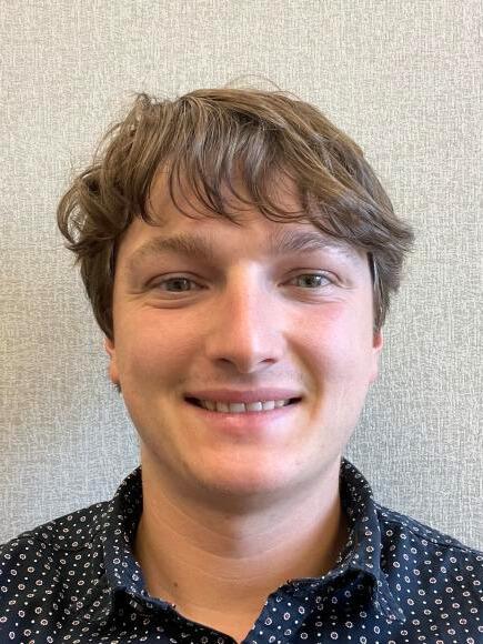 Man smiles against neutral background 