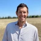Man smiles in broad field 