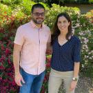 A man and a woman standing in a garden-like area with flowering plants.