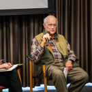 woman and man sitting in chairs on a stage